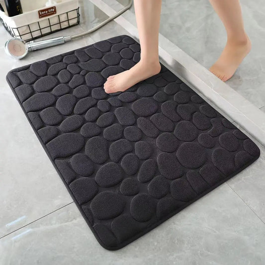 Black cobblestone bath mat on a bathroom floor