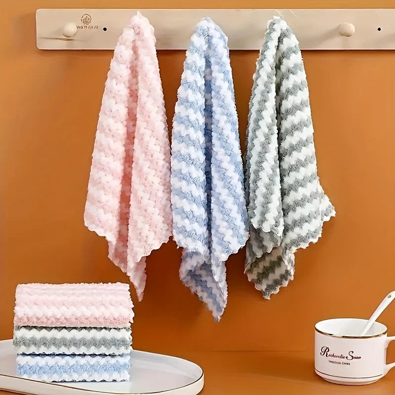 Three striped dish cloths in pink, blue and gray hanging on a kitchen rail