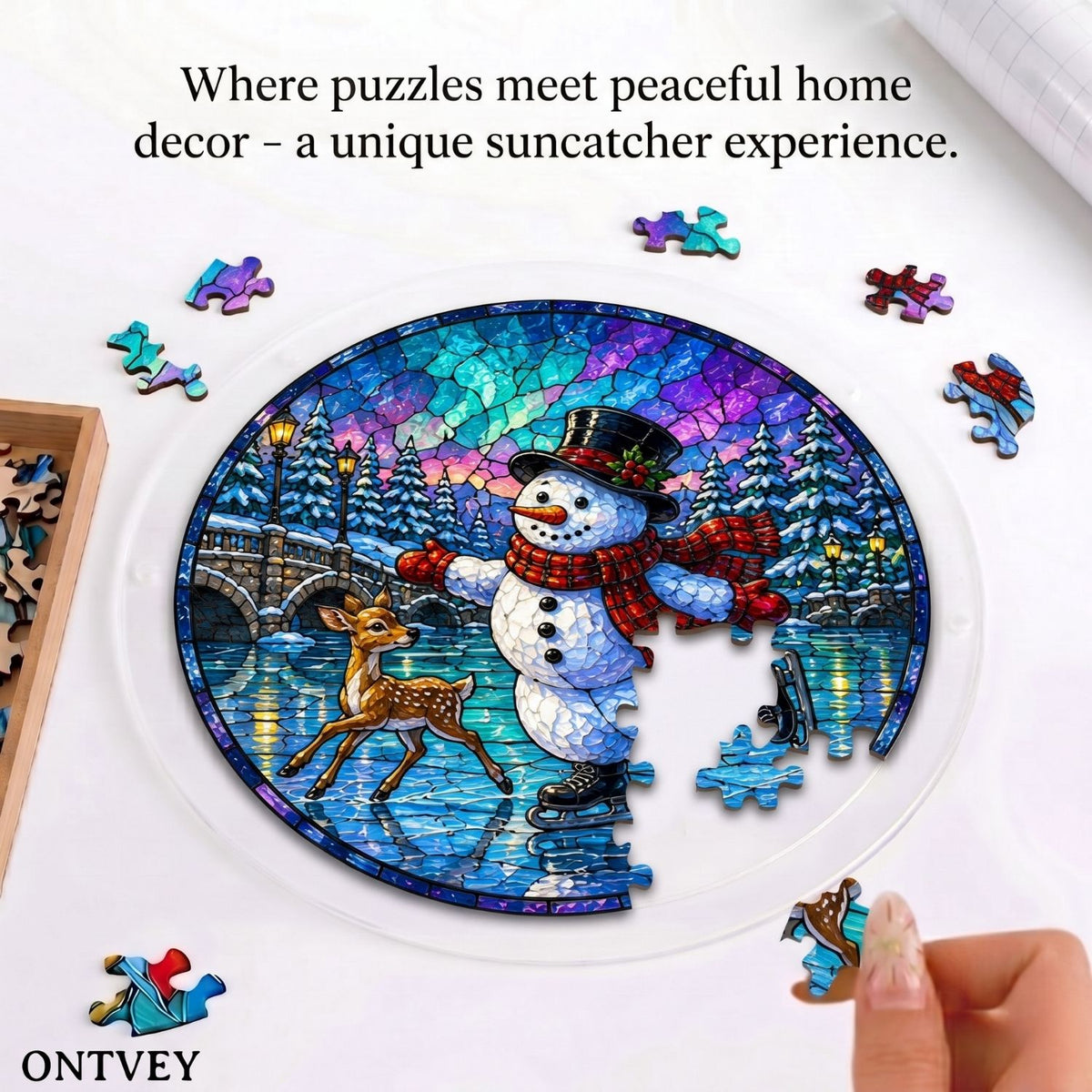 Hands assembling the Skating Snowman & Deer acrylic jigsaw puzzle suncatcher on a table