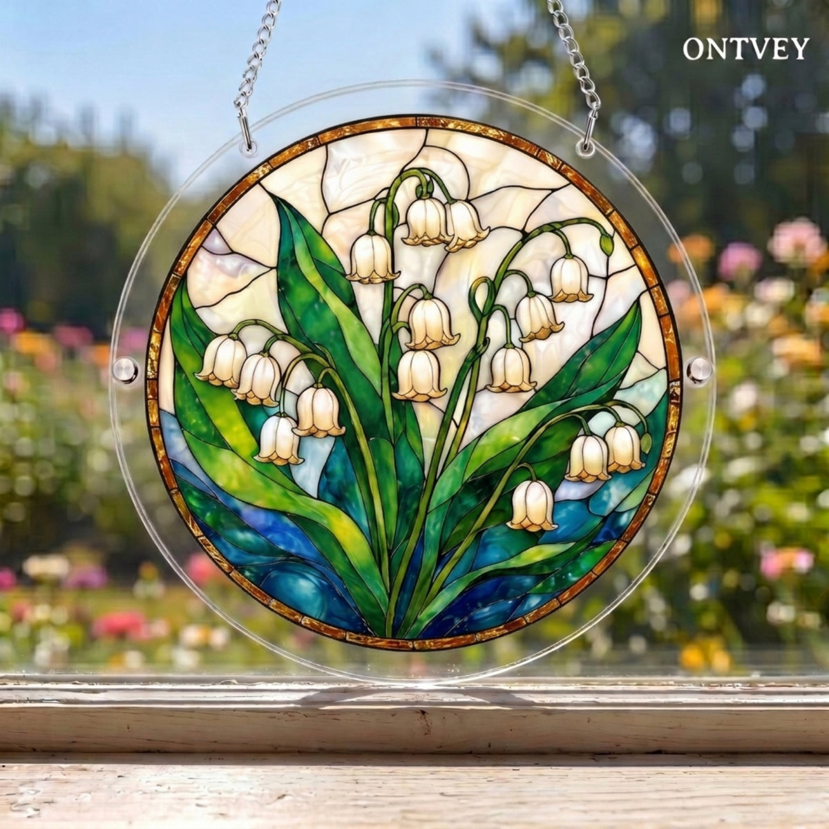 Lily of the Valley puzzle suncatcher hanging in a window with a garden behind it